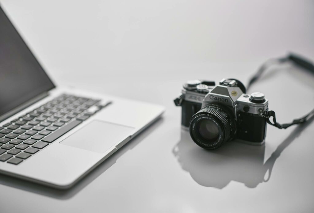 Black and Silver Dslr Camera beside Gray Laptop